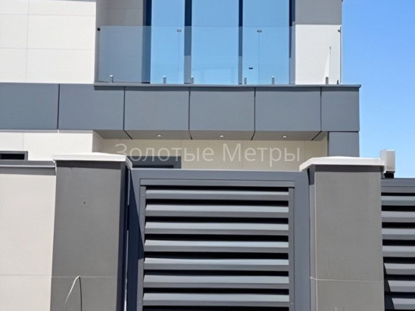Фасад современного жилого комплекса с балконом и металлической дверью.