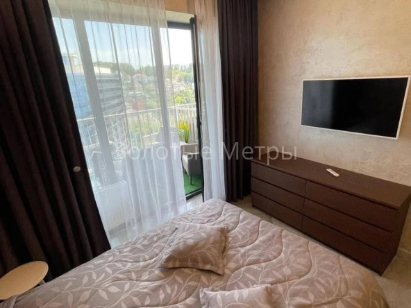 Комната в апартаментах с видом на море, телевизор и балкон.